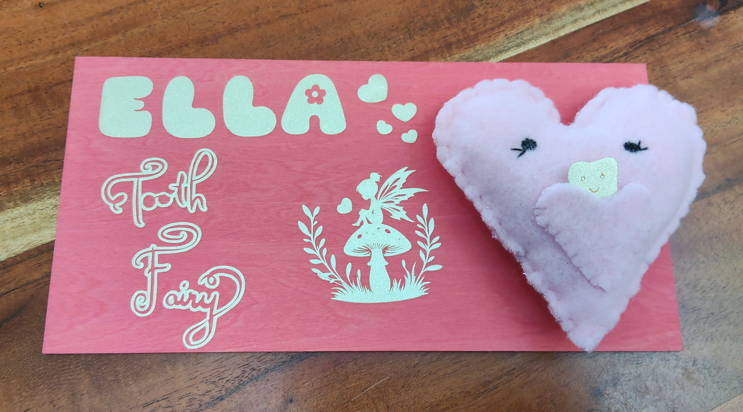 Heart-shaped plush lost tooth pillow with 'Personalised Tooth Fairy' on a pink wooden board 