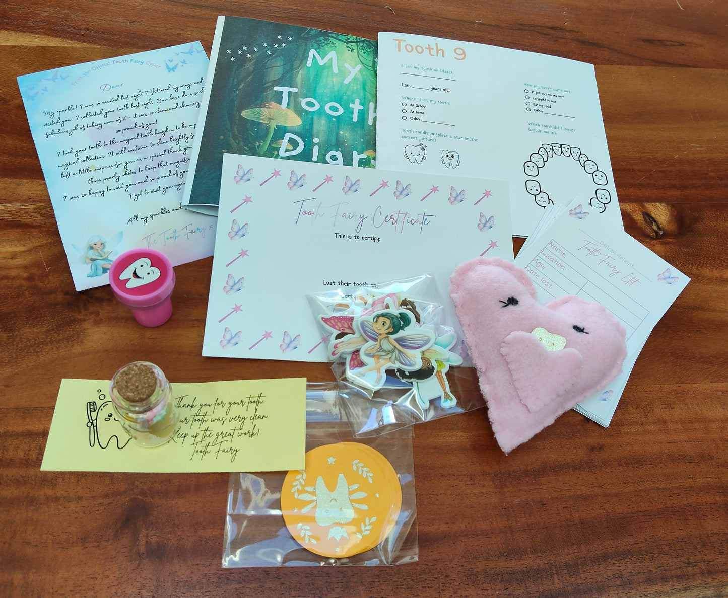 Collection of items including a tooth fairy letter, tooth fairy certificate, heart-shaped tooth pouch, tooth fairy coins, tooth fairy receipts, and a tooth fairy message in a bottle. 