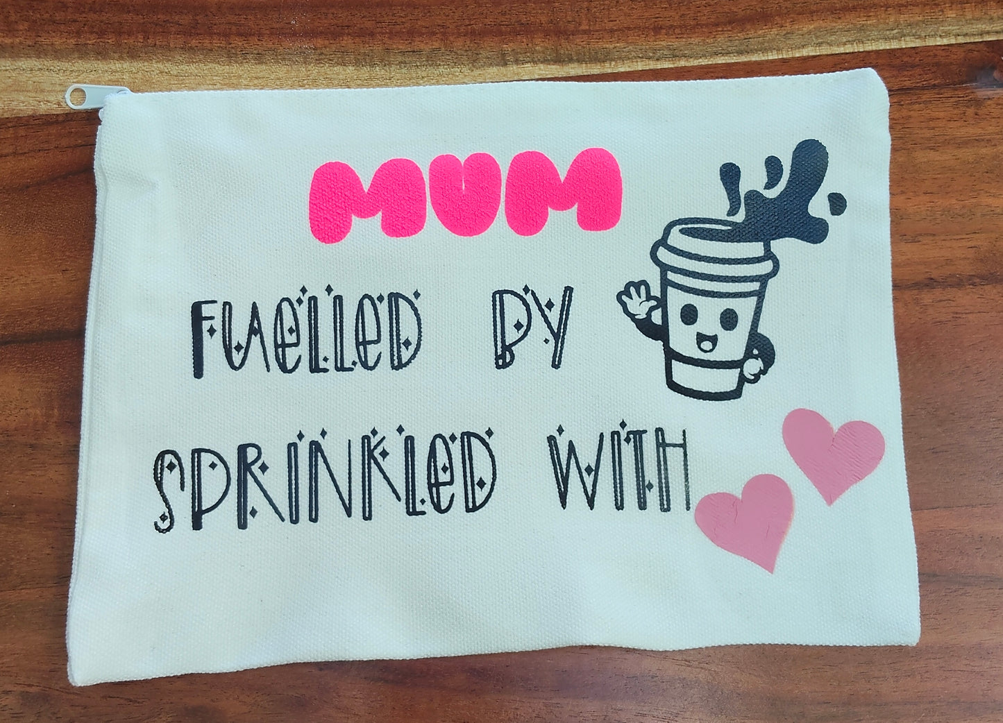 White zip pouch with text 'Mum fuelled by (coffee cup image) sprinkled with (love hearts image). 